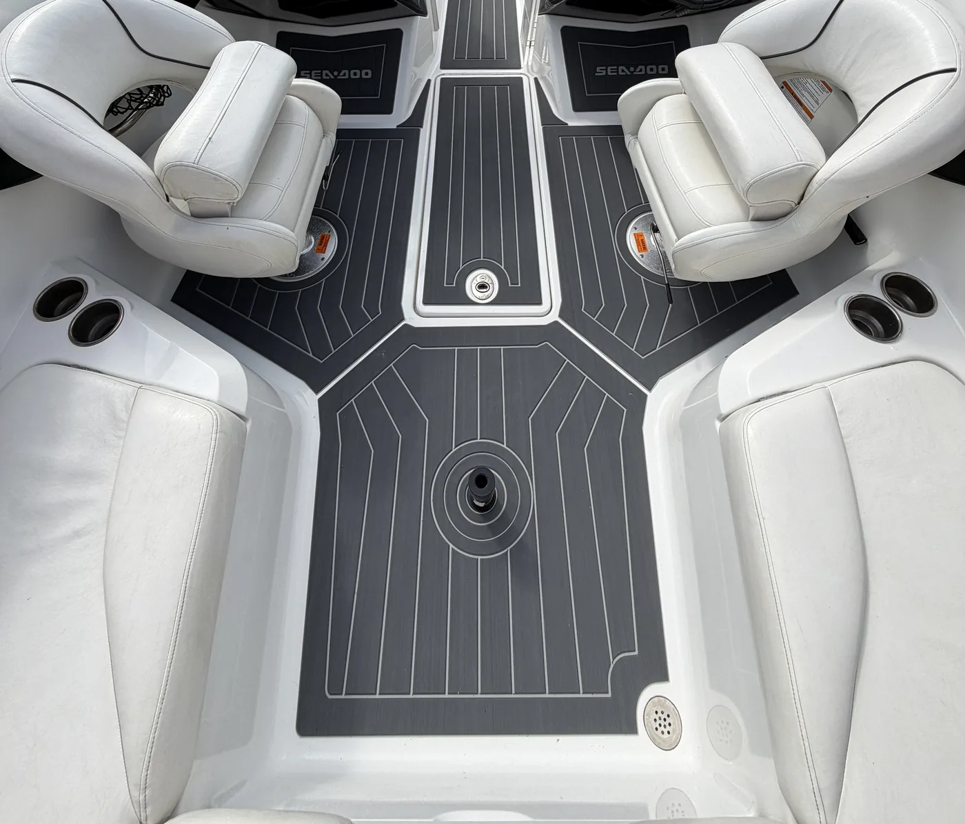 A 2010 Sea-Doo 210 Challenger cockpit with dark grey and light grey plank pattern flooring, seen from the bow